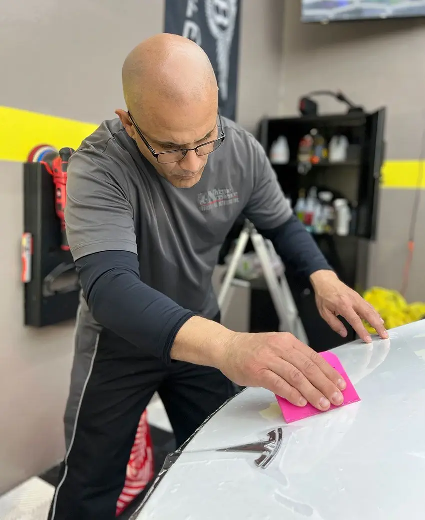 Protective film squeegeed across a body panel